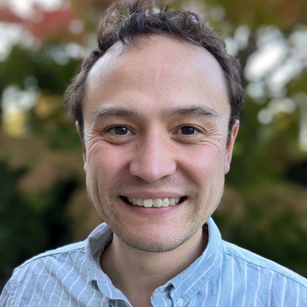 Smiling headshot of Josh Lim, a mixed British Malaysian male with brown hair and creases around the eyes where he's smiling.